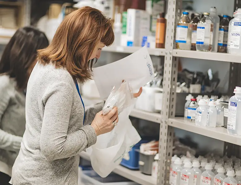 Due dottoresse controllano i farmaci sugli scaffali della farmcia della fondazione Gigi Ghirotti di Genova.