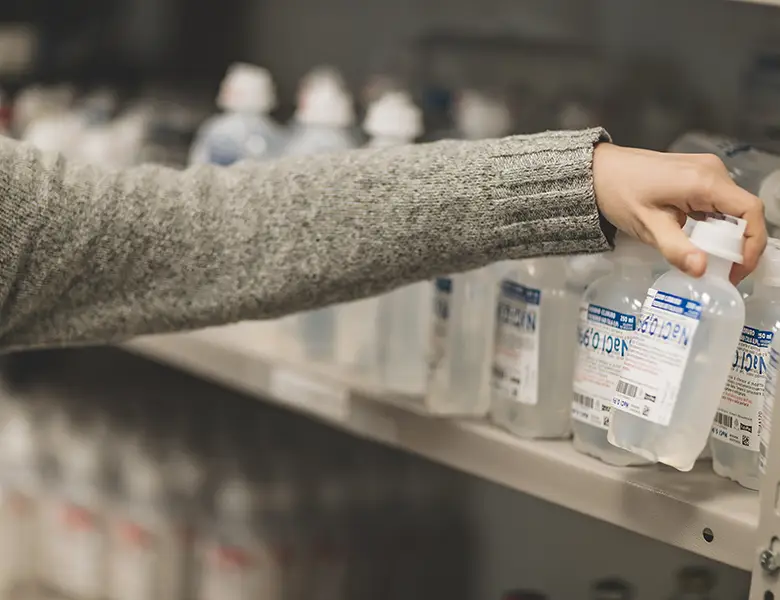 Si vede il braccio di una infermiera che preleva farmaci da uno scaffale nella farmacia della fondazione.