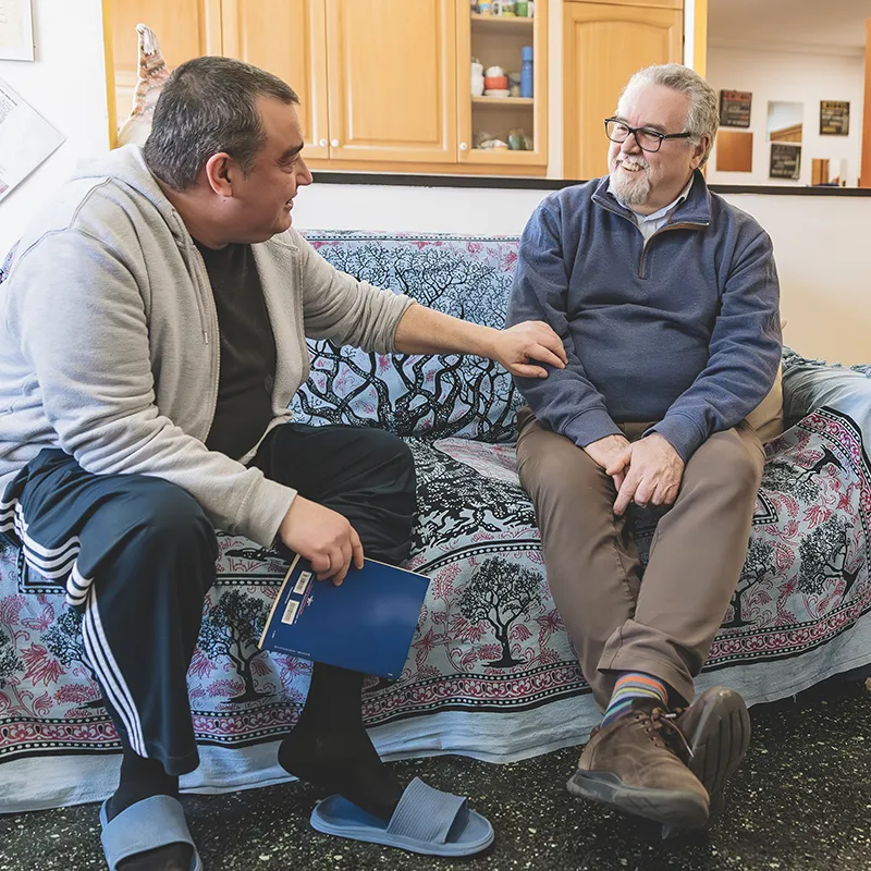 Paziente ed assistente conversano seduti sul divano della cucina di uno degli hospice.