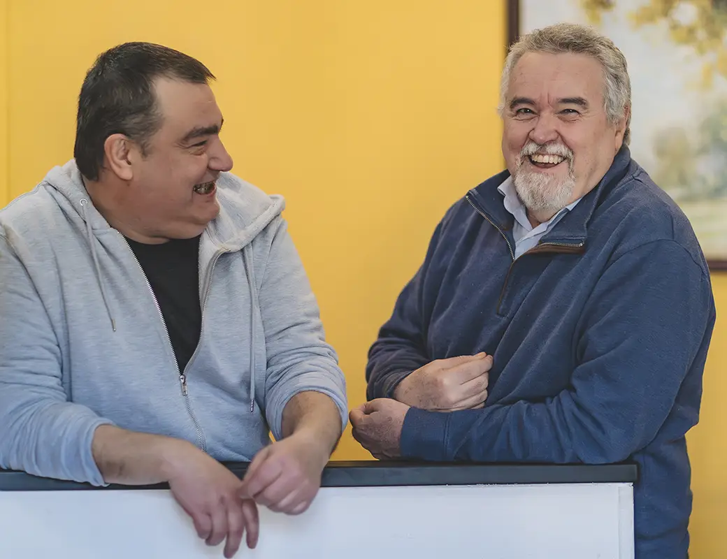 Un volontario della fondazione ed un ospite in un incontro si parlano e sorridono.