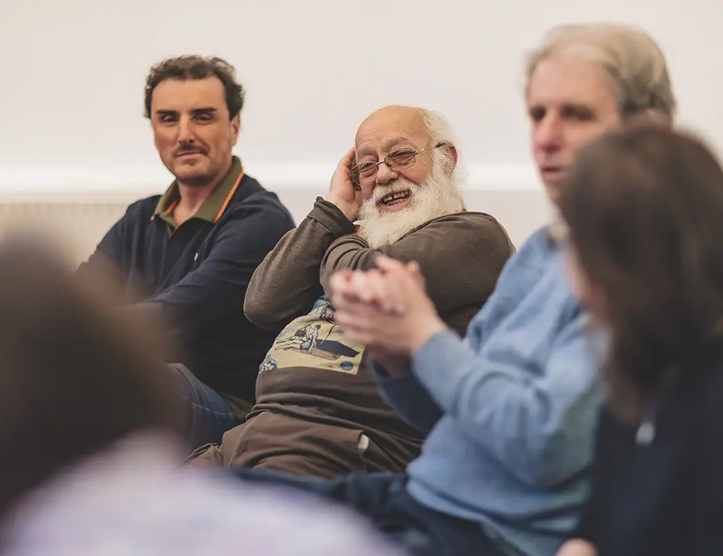 Fondazione Gigi Ghirotti l'iniziativa Café Alzheimer è illustrata in questa foto dove un gruppo di pazienti ed ospiti discute amabilmente.