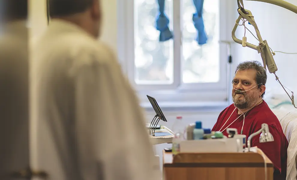 Uno degli ospiti del centro hospice, a letto nella sua stanza a colloquio con il medico.
