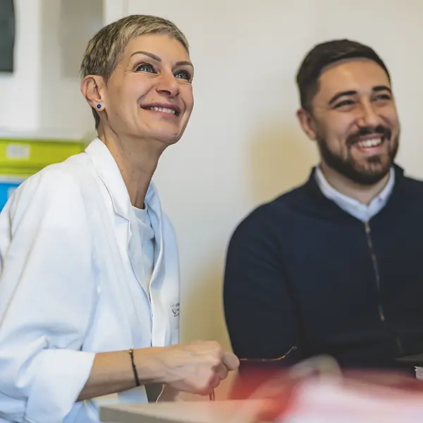 Una psicologa ed uno psicologo della fondazione Gigi Ghirotti conversano sorridenti.